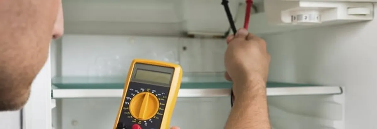Refrigerator repair technician testing electrical components with a multimeter in Columbus, OH
