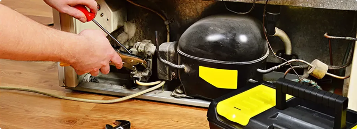 Refrigerator repair technician fixing the compressor and wiring in Columbus, OH